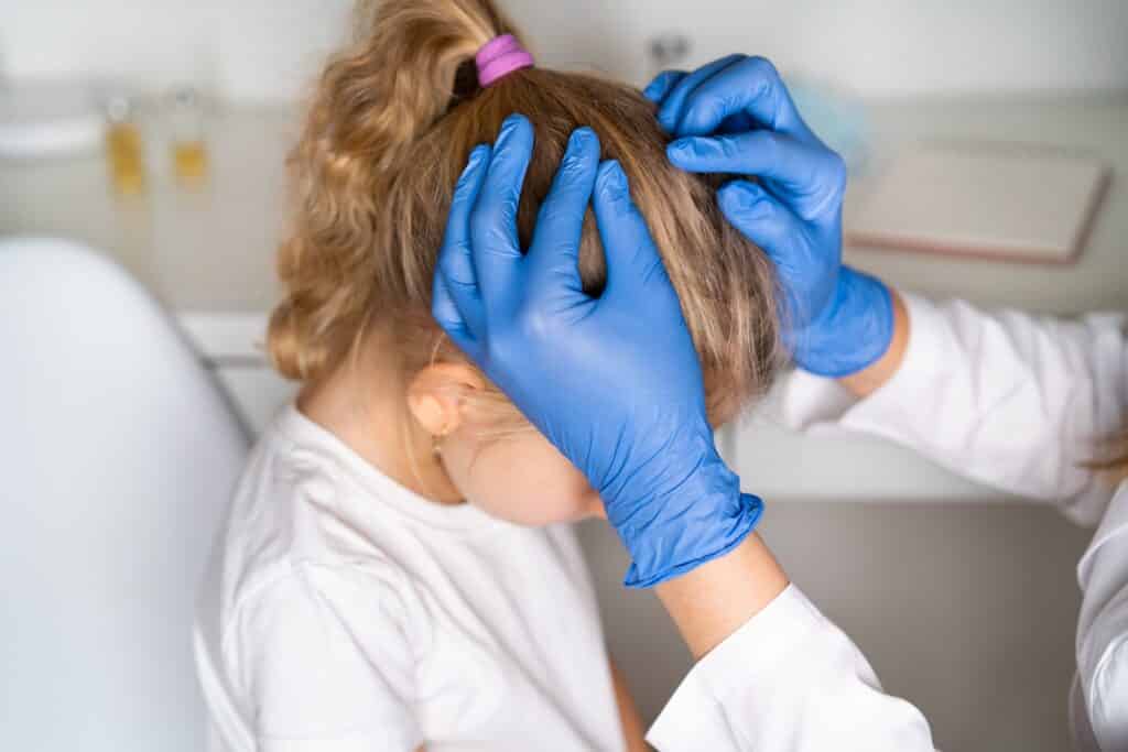 Doctor looking for a lice on the girl's head.