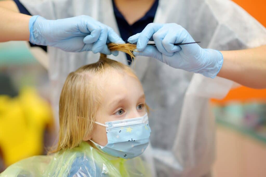 a preschooler boy with a facemask is getting a haircut