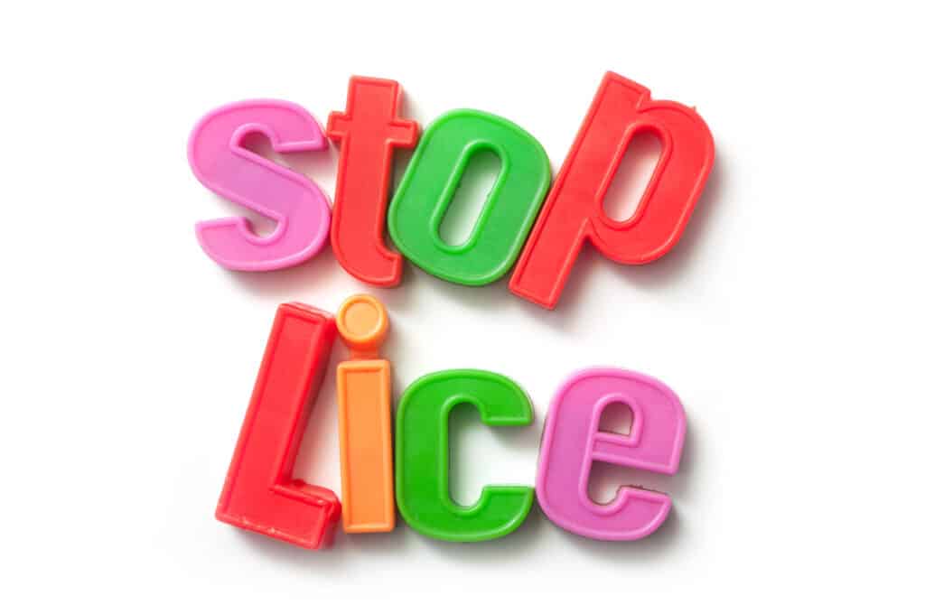 Closeup of colorful plastic letters on white background - Stop Lice.