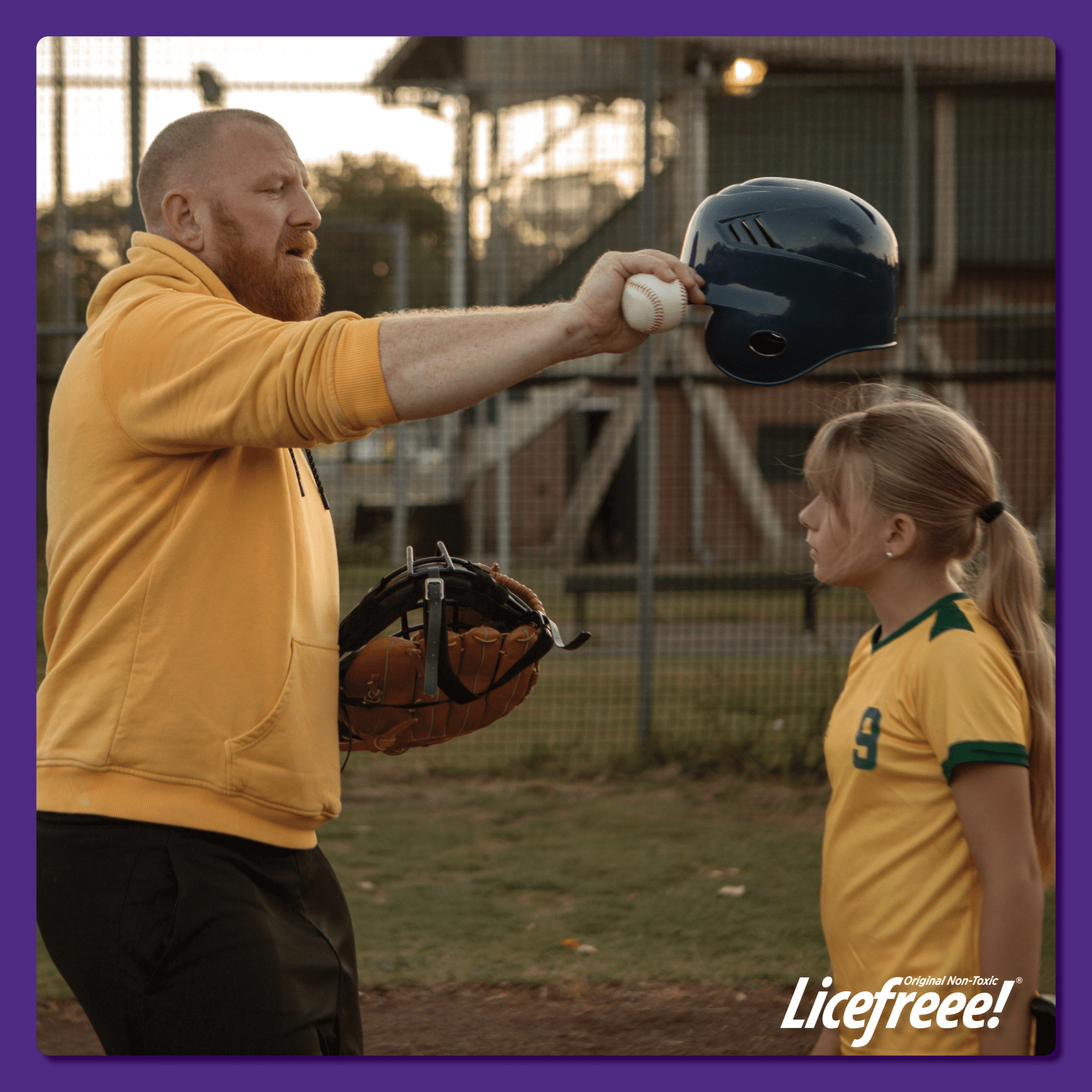 A baseball coach is about to put on a batting helmet on a young girl's head.