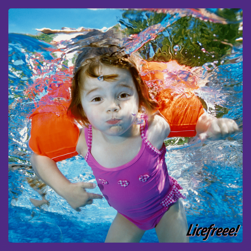 Una linda niña con un traje de baño morado fue fotografiada bajo el agua.