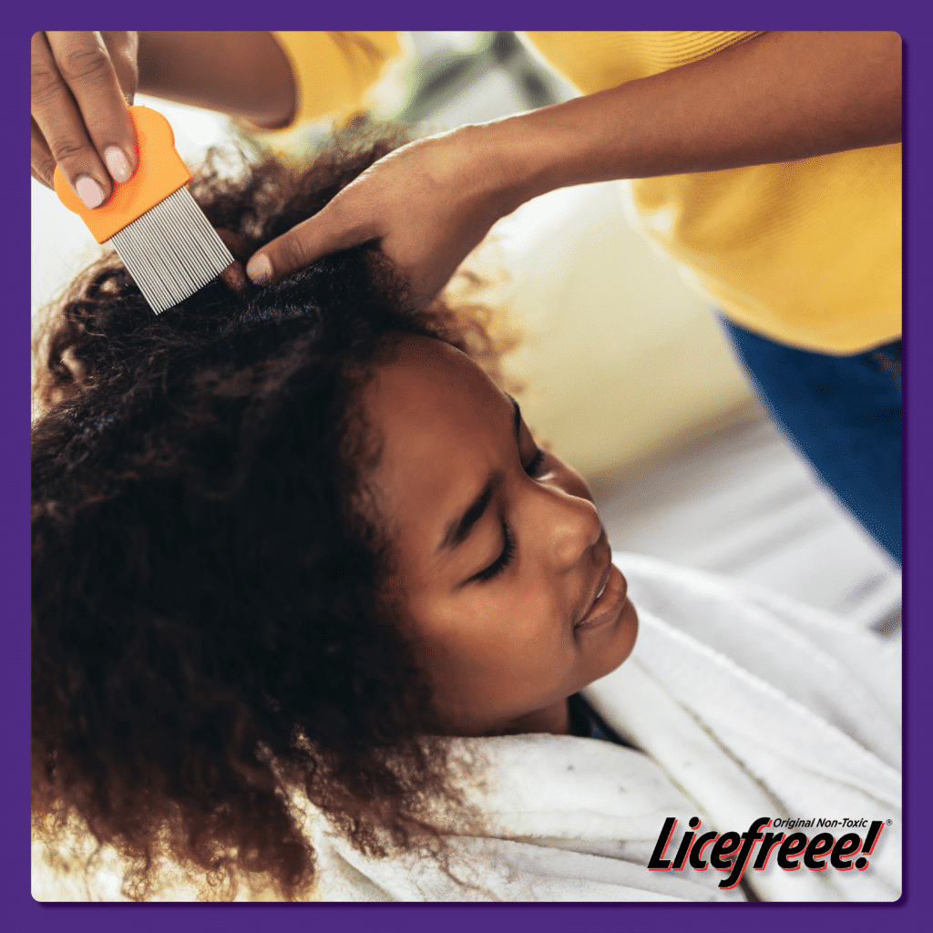 A curly-haired young black girl is being combed to check for lice.